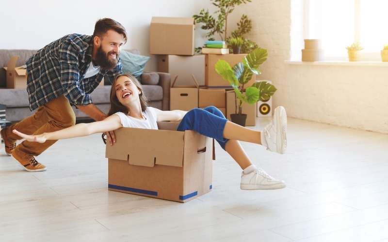 tips for decluttering before moving - shows images of husband pushing wife inside a packing box