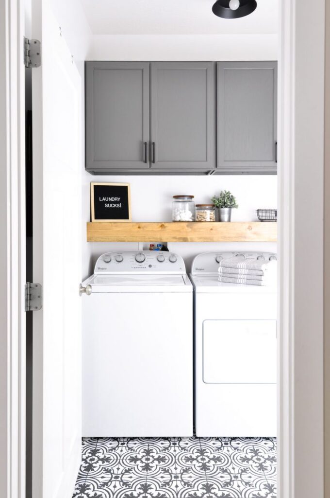 A laundry room with grey cabinets and a decorative floor