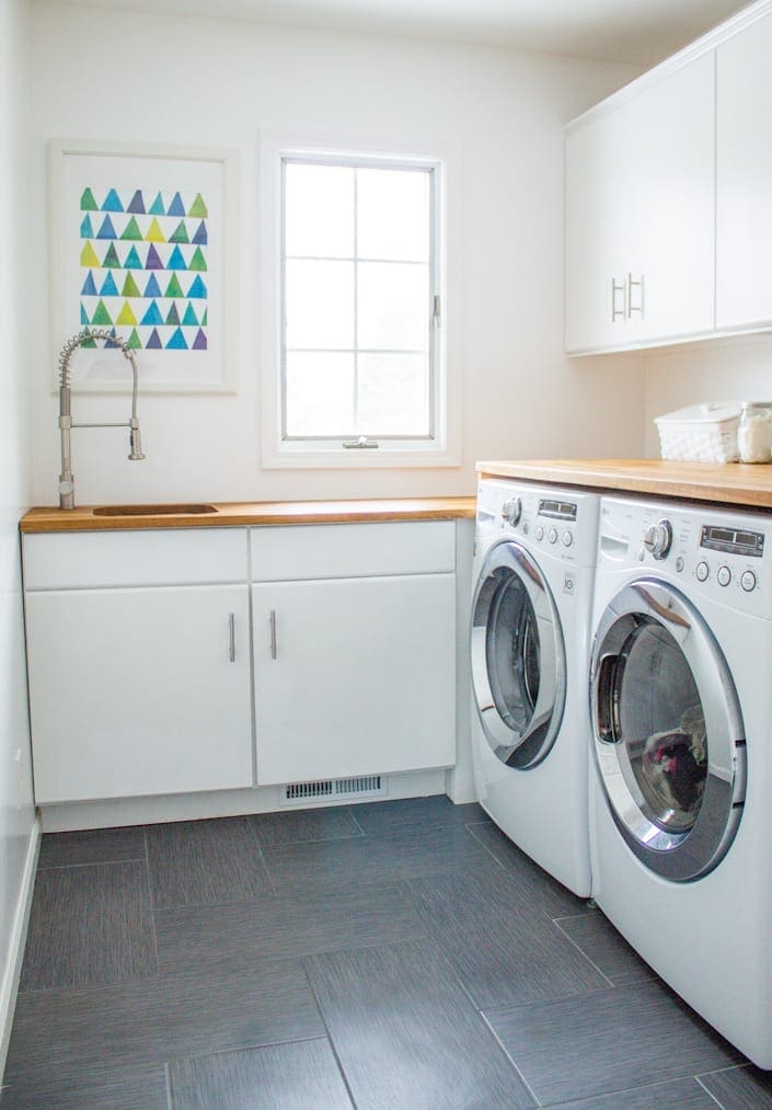 A piece of art hangs above the sink in a laundry room