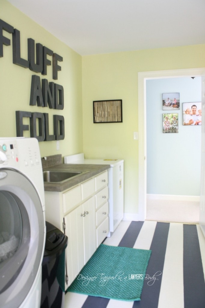 A laundry room with striped floors and the words fluff and fold on the wall