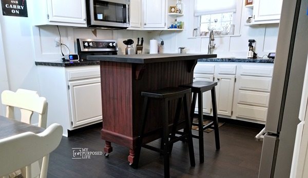 A kitchen island with wheels and 2 stools