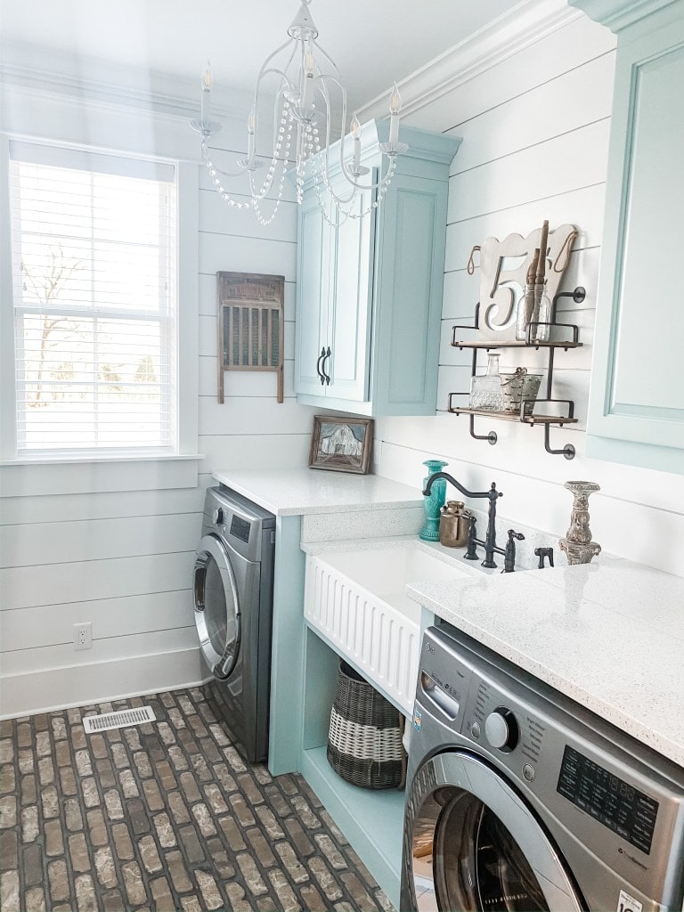 A laundry room with brick floor and a chandelier 