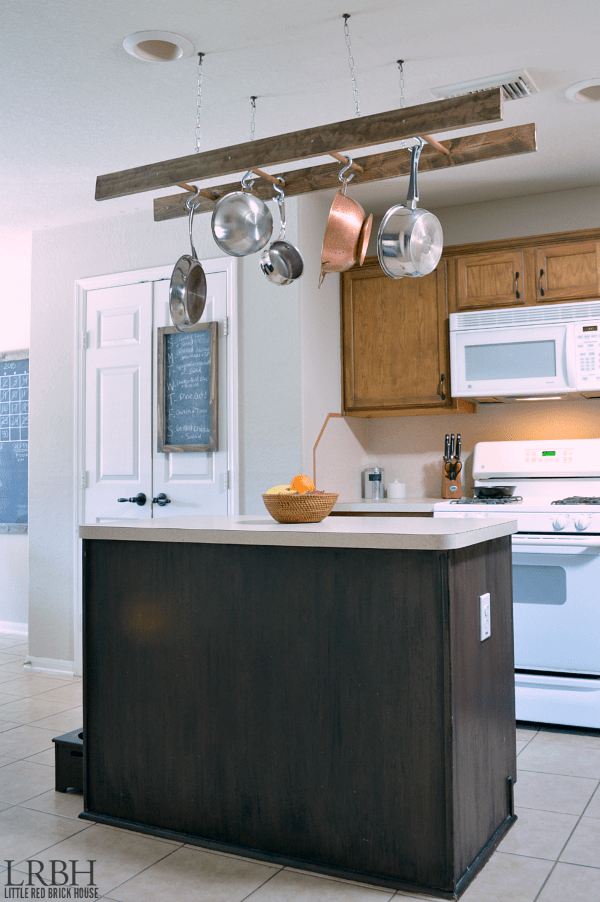 Pots and pans hanging from the ceiling above the kitchen island