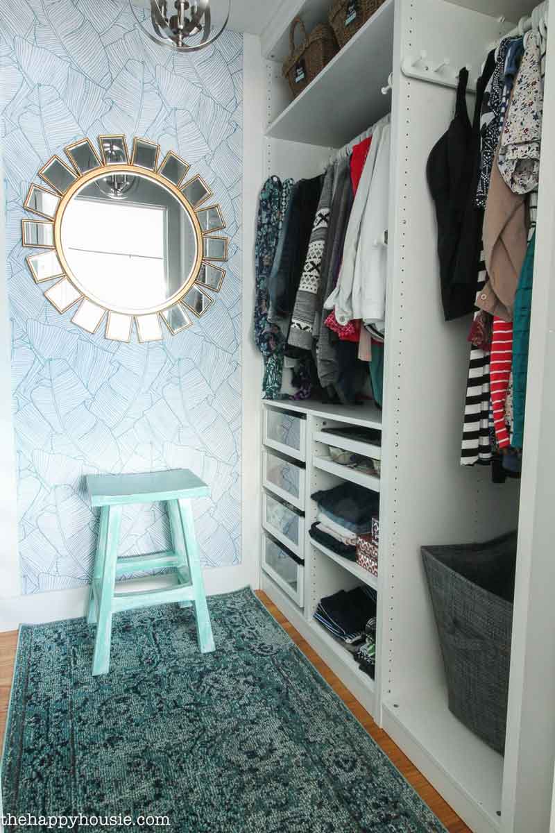 An organized closet with a blue wall and mirror