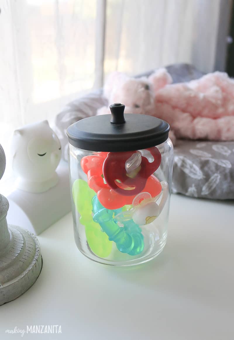 A Jar of pacifiers on a changing table 