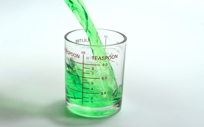 Image of green liquid being poured in a measuring cup