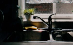 Photo of empty sink and a sink with dishes by a window at night time