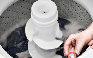 image of hand holding dishwashing pod over a washing machine