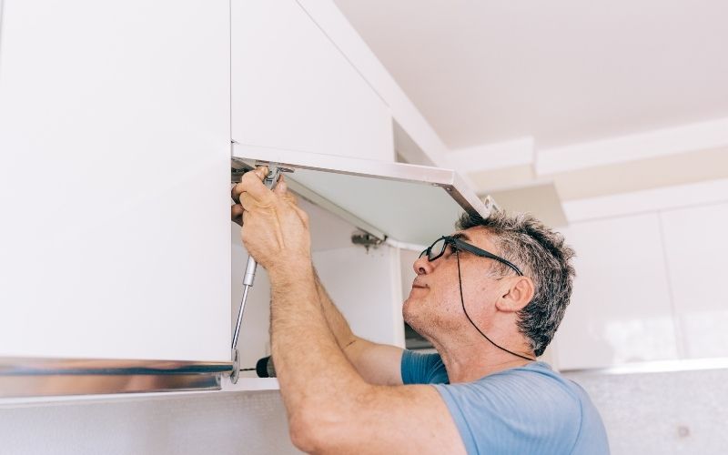 Image of a man removing the hinges in the cabinet