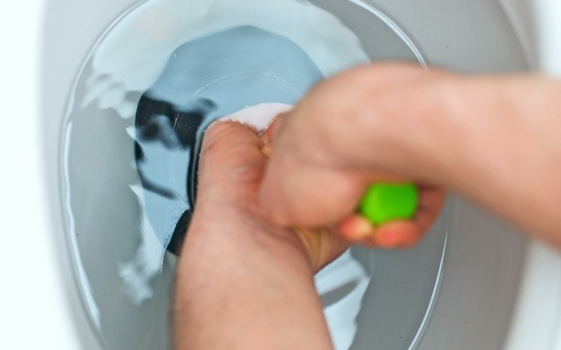 Image of a pair of hands holding a plunger over a toilet bowl
