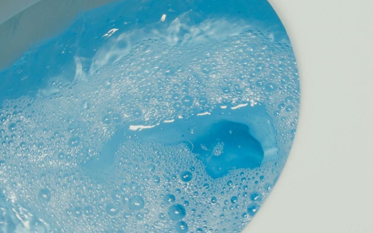 Photo of a toilet with blue water being flushed down