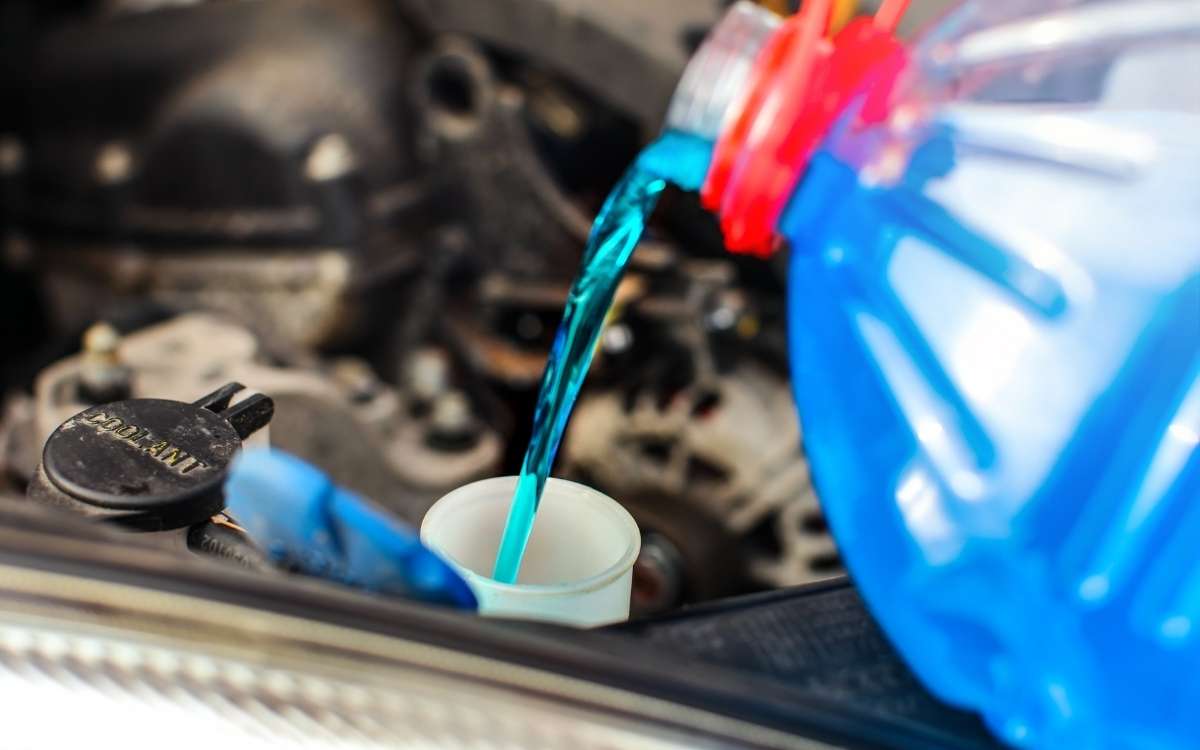 Image showing a plastic container with blue liquid being poured in the engine