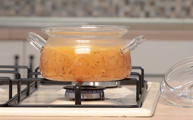 photo of a cooking glass ware with sauce on a stove top