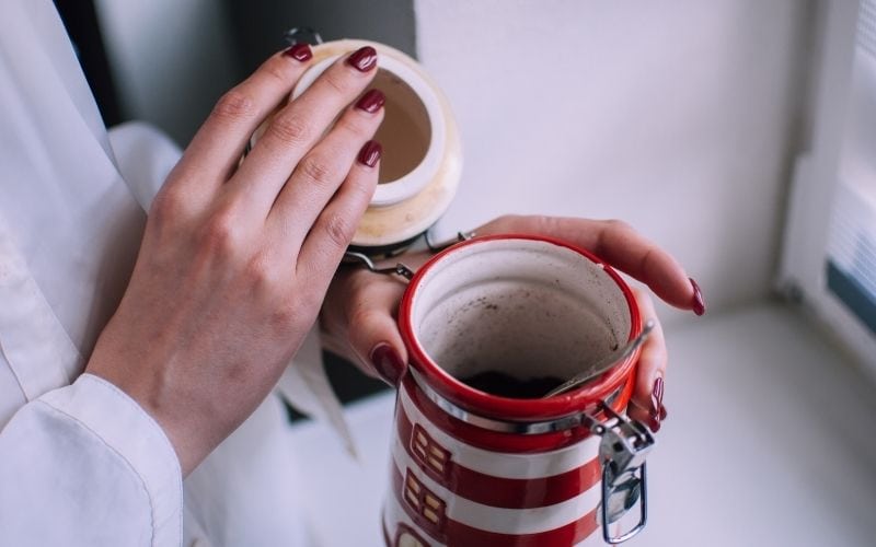 Image of a pair of hands holding a canister with coffee