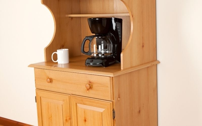 Image of a brown cabinet with coffee maker and a mug