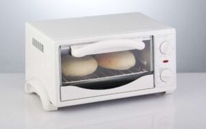 Photo of a white oven toaster with bread inside in white background