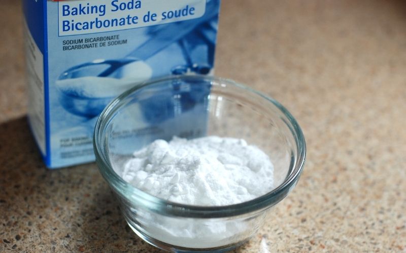 Image of a bowl with white powder and a blue box of baking soda