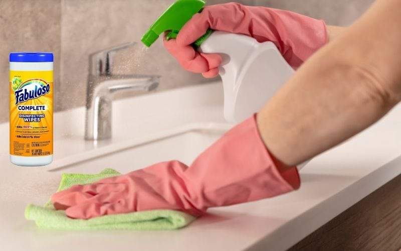 Picture showing a person cleaning a surcae with a rag while spraying