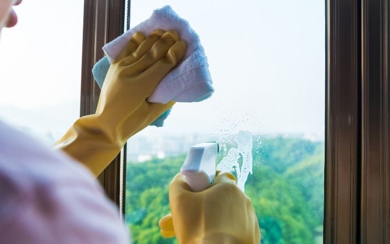 Picture showing a pair of hands cleaning the glass with a rag while spraying