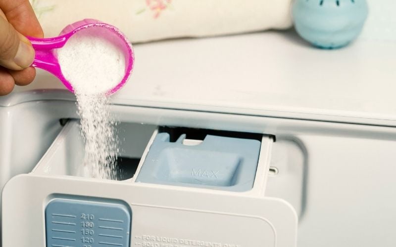 Photo with white powder being poured in the washing machine 