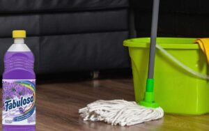 Image of a green bucket and a mop on wooden floor