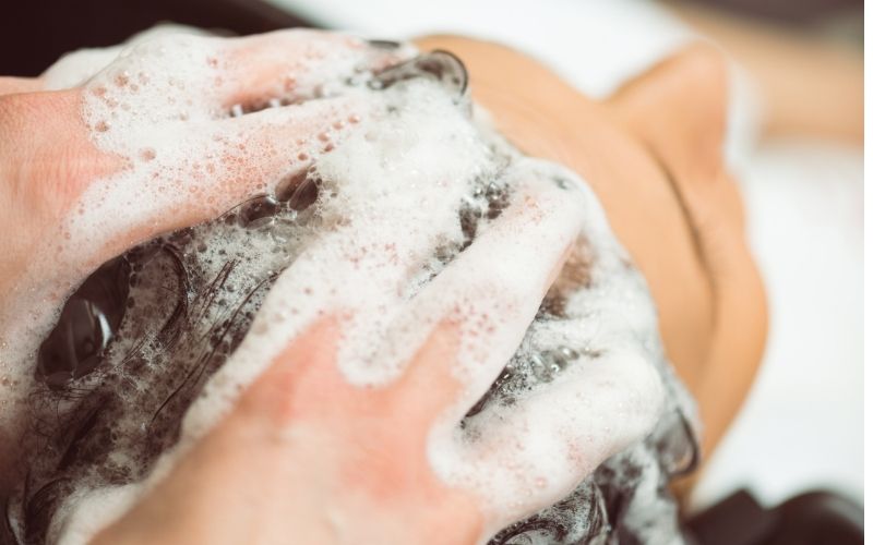 Photo of a pair of hand shampooing someone's hair