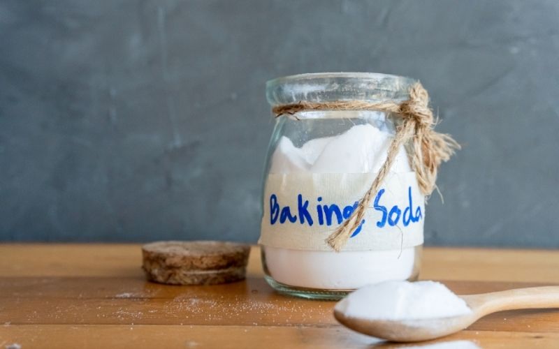 Photo of baking soda in a jar and spoon on a wooden table top