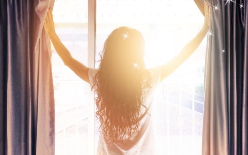 Photo of a woman stnding by the window on daylight