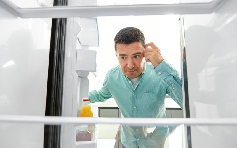 Photo of a person looking at the empty shelf of what it looks like the inside of a refrigerator