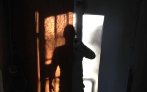 Photo showing a dark room with a person's shadow by the door