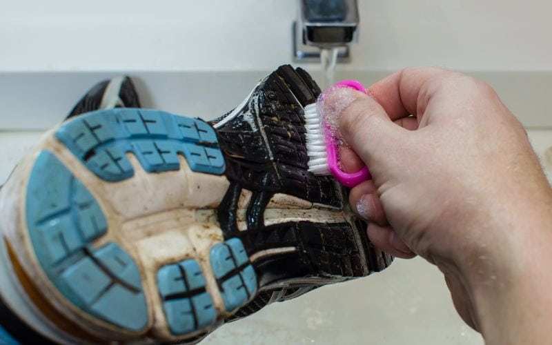 Brushing the under side part of the shoes using brush over a sink