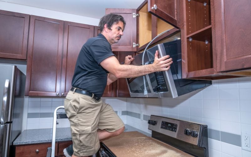 A man installing an oven in the kitchen