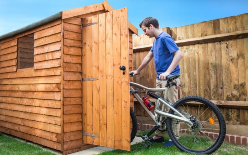 Photo of a man moving a bike into the shed from outside