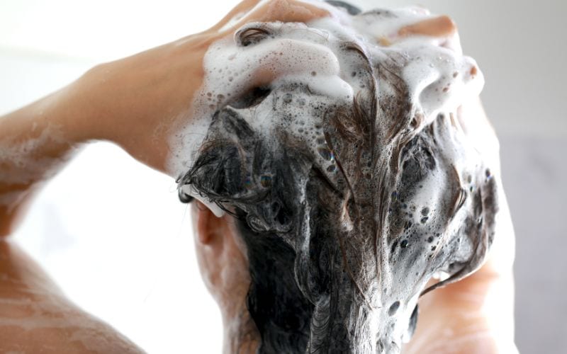 a woman massaging her hair with shampoo