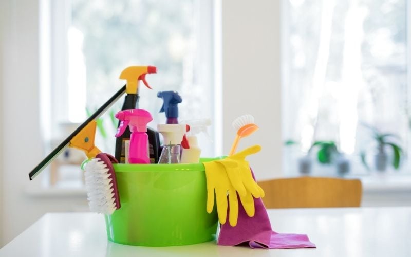 Photo of a green pail full of cleaning supplies placed on a table