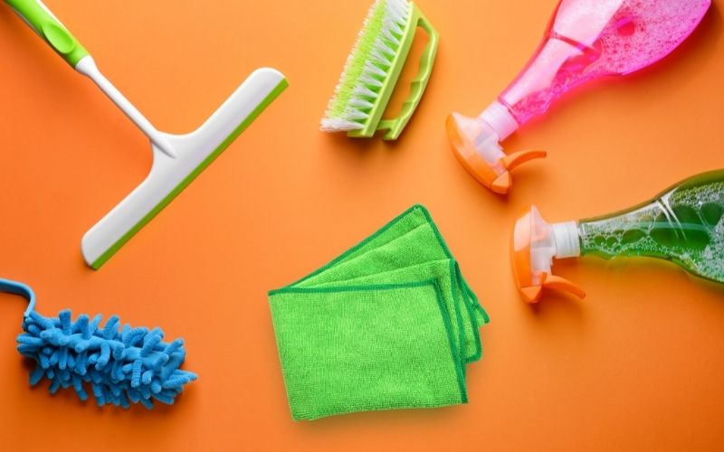 Image showing cleaning supplies needed to clean shower glass doors in orange background
