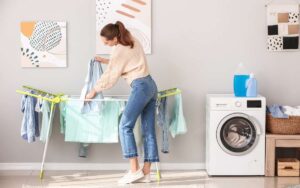 Photo of a woman hanging the clothes beside a washing mashine inside the laundry room