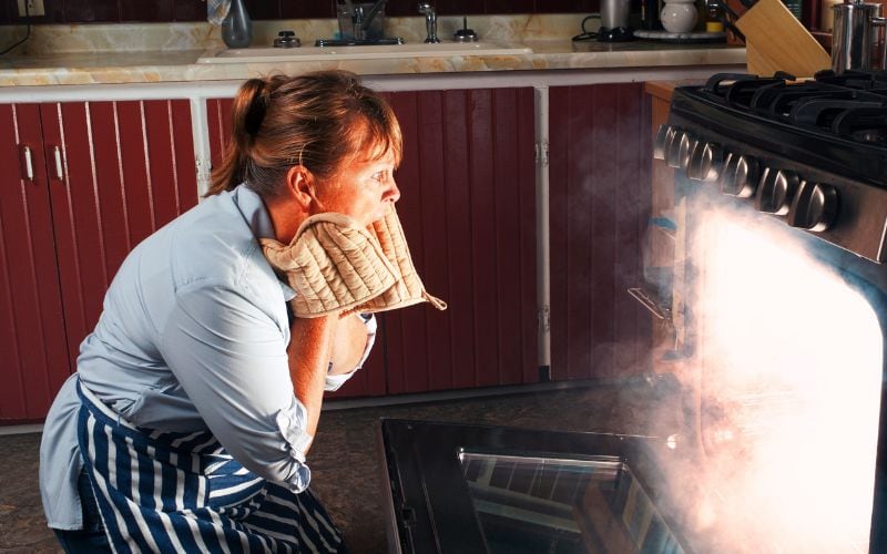 A woman worried about something burning inside the oven