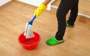 A person holding a mop over a red basin
