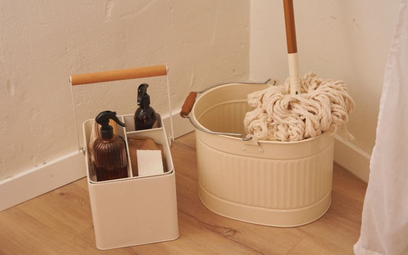 A clean mop on a bucket and several cleaning products.
